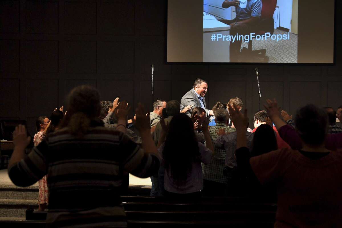 Worship leader Jeremy Fletcher gathers at the altar in praying overr an annninted prayer cloth for during a prayer vigil for Orange County Sheriff's officers Dru Crochet and Scott Barnes and Orange City. Policeman Howard DeVault at Eastgate United Pentecostal Church in Vidor Monday. The three officers are battling serious illesses, prompting the community to rally together in prayers and support. Photo made Monday, April 12, 2021 Kim Brent/The Enterprise