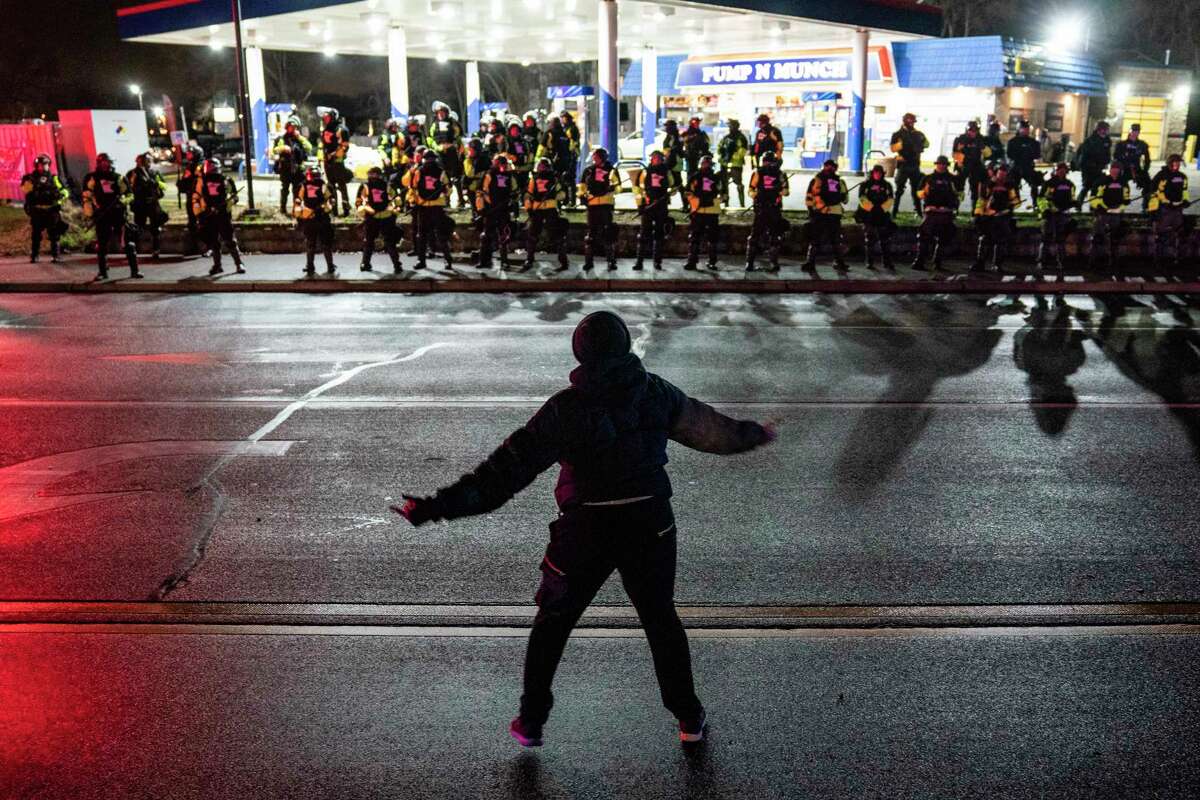 A demonstrator heckles authorities who advanced into a gas station after issuing orders for crowds to disperse during a protest against the police shooting of Daunte Wright, late Monday, April 12, 2021, in Brooklyn Center, Minn.