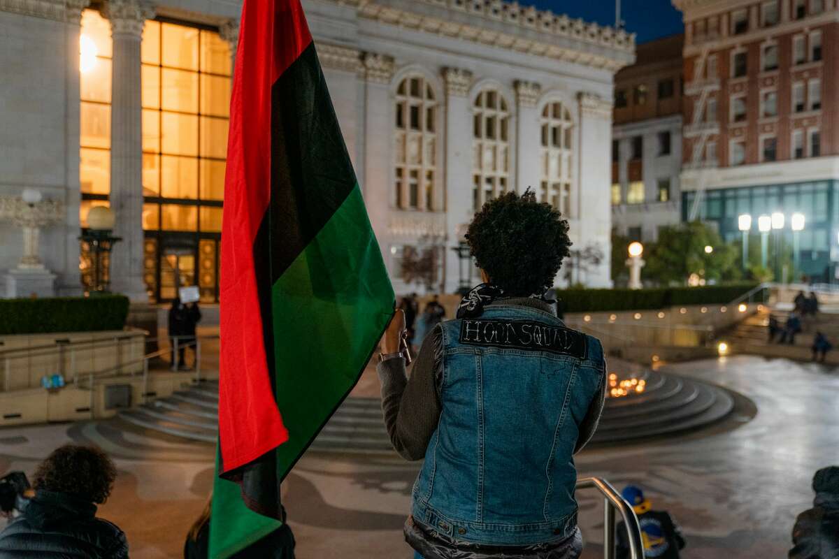 Tweedy from Tha Hood Squad holds a Pan-African flag during the vigil.