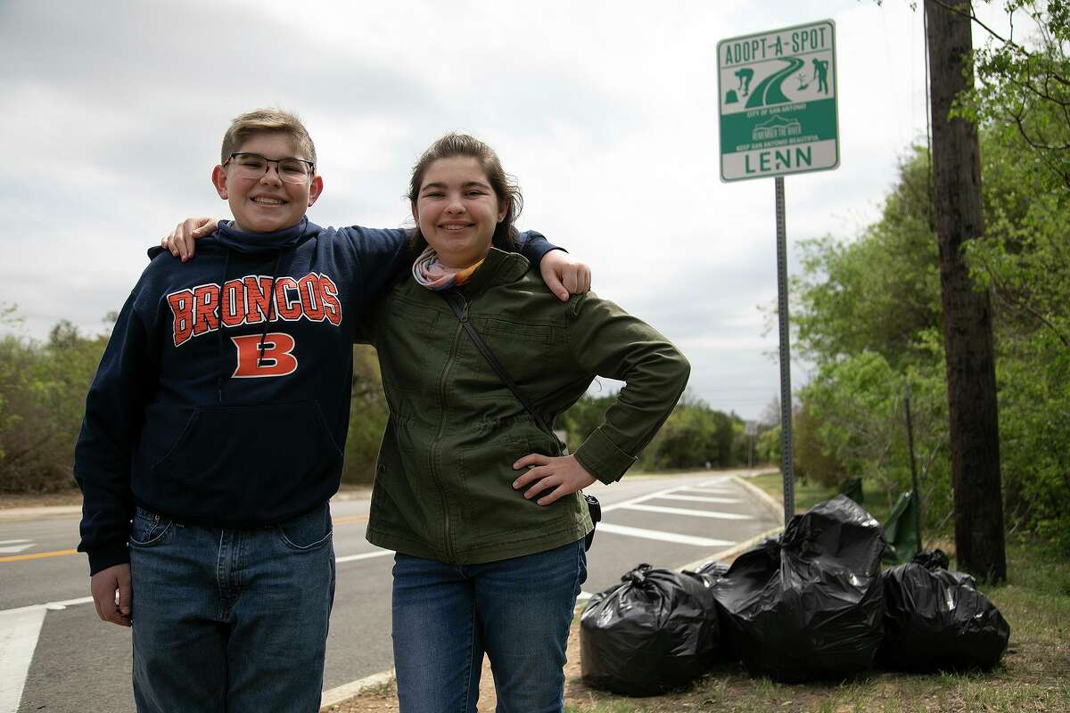 Nichole Dopp, 17, and her brother, Louis Dopp, 14, stand next to bags of trash they picked up along the section of Kyle Seale Parkway their family has adopted to keep clean.