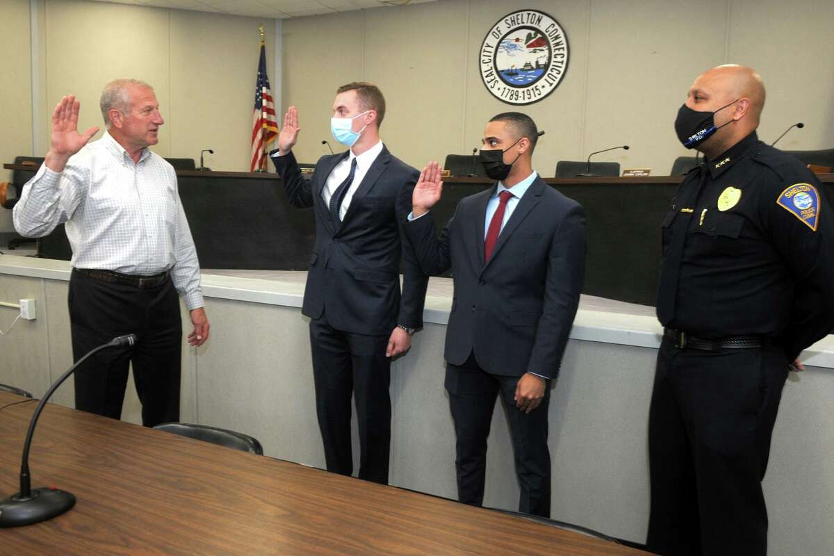 From left, Mayor Mark Lauretti swears in two new recruits to the Shelton Police Department, Steve Kernstock and Lonnie Blackwell, at Shelton City Hall in Shelton, Conn. April 13, 2021. They are seen here with Police Chief Shawn Sequeira, right.