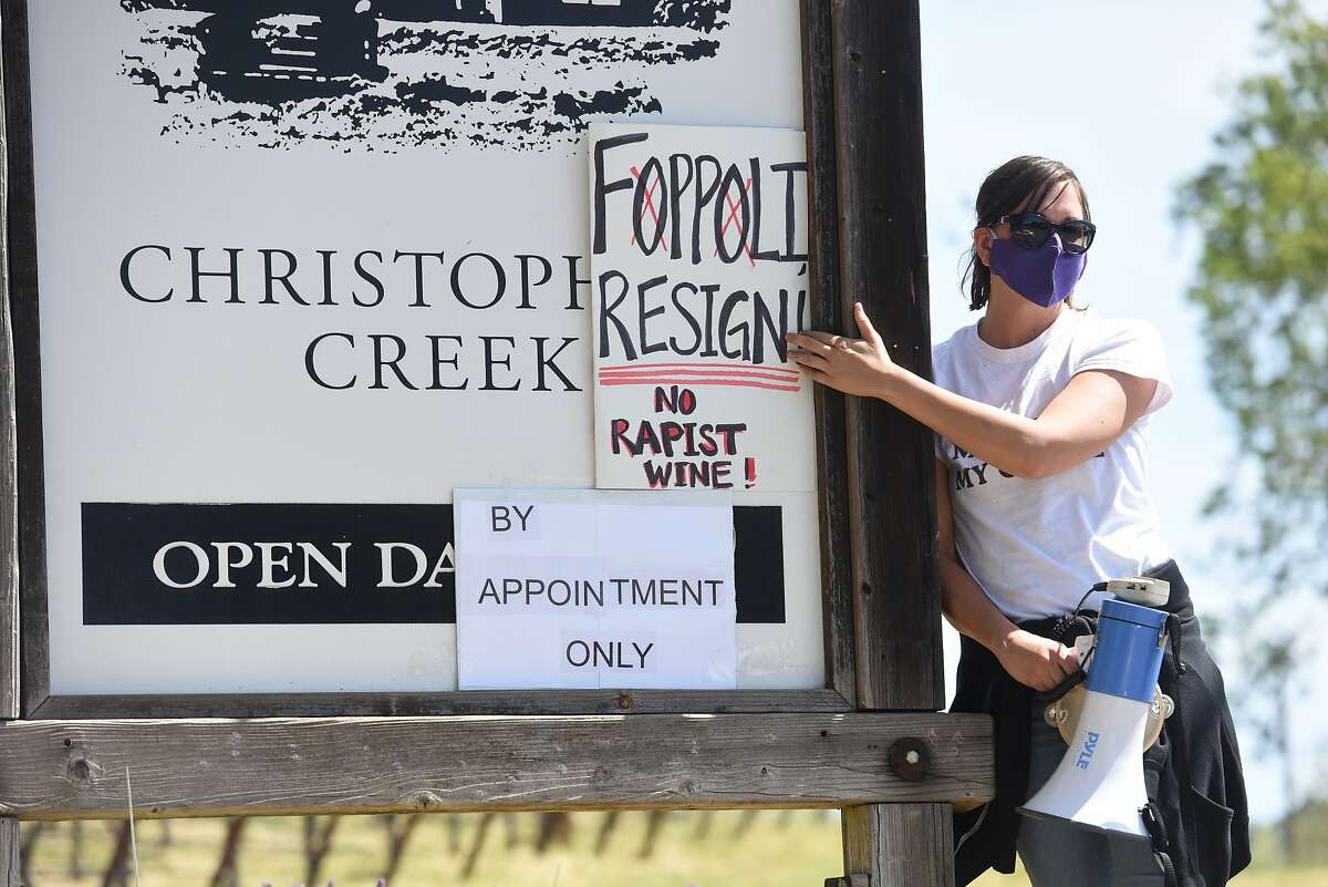 Hollie Clausen of Santa Rosa holds a sign calling for Windsor Mayor Dominic Foppoli to resign on the sign for Christopher Creek Winery at a rally outside Christopher Creek Winery in Healdsburg, Calif. on Sunday, April 11, 2021. Mayor Foppoli is a co-owner of Christopher Creek Winery but Joe Foppoli, Dominic’s brother, recently announced that Dominic is no longer a part of the business. Clausen organized the rally at the winery to call attention to the business. Calls for Dominic to resign follow allegations of sexual assault reported by The San Francisco Chronicle.
