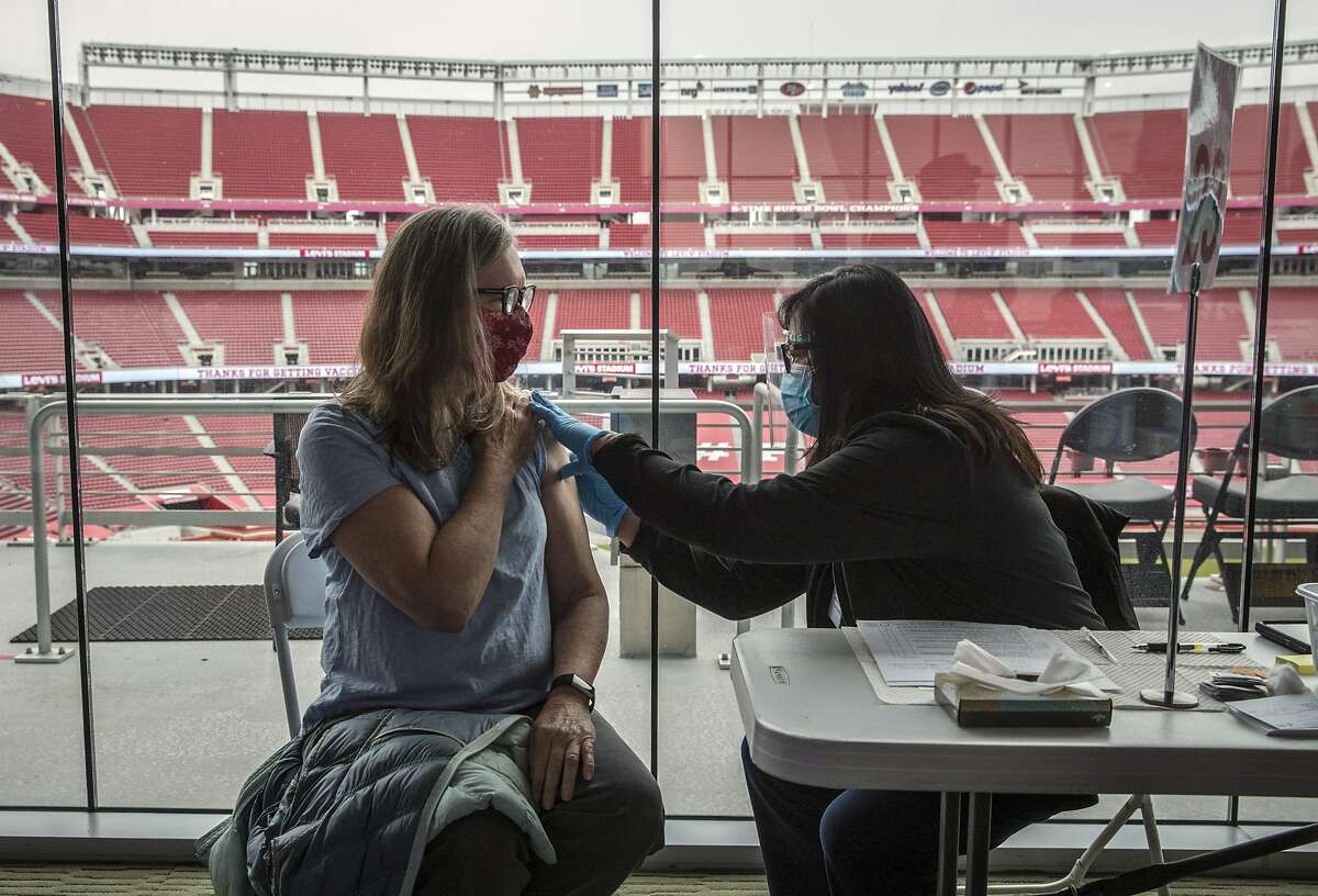 Clinical nurse Lynette Ancheta, right, checks Lynda Barbieri’s arm before giving her the Pfizer COVID-19 vaccine at Levi’s Stadium in Santa Clara, Calif., on Feb. 9, 2021. Levi’s Stadium was used as the mass vaccination site.