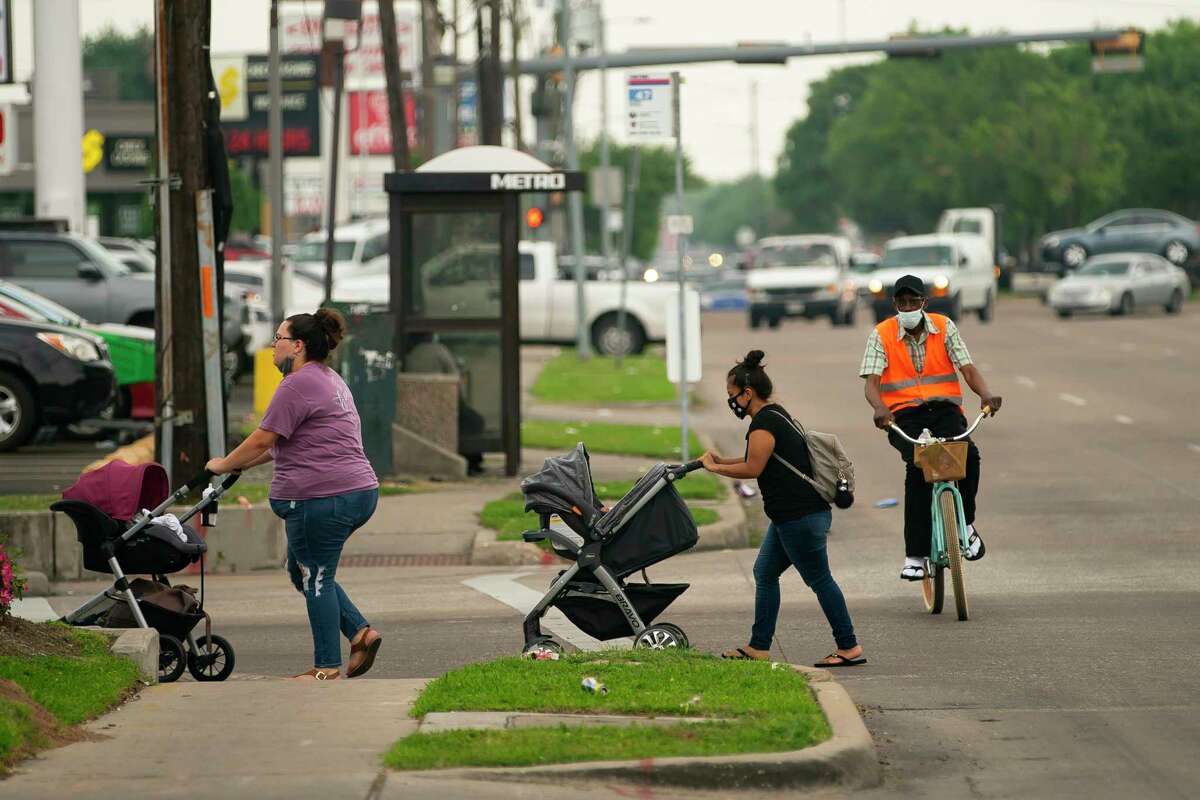 Pedestrians and a cyclist traverse Hillcroft Avenue north of Bellaire Boulevard on Tuesday, April 13, 2021, in Houston. The city is has since begun work on Hillcroft that would take the eight-lane street down to six lanes, adding new bike lines and attempting to make the stretch of road more pedestrian friendly.