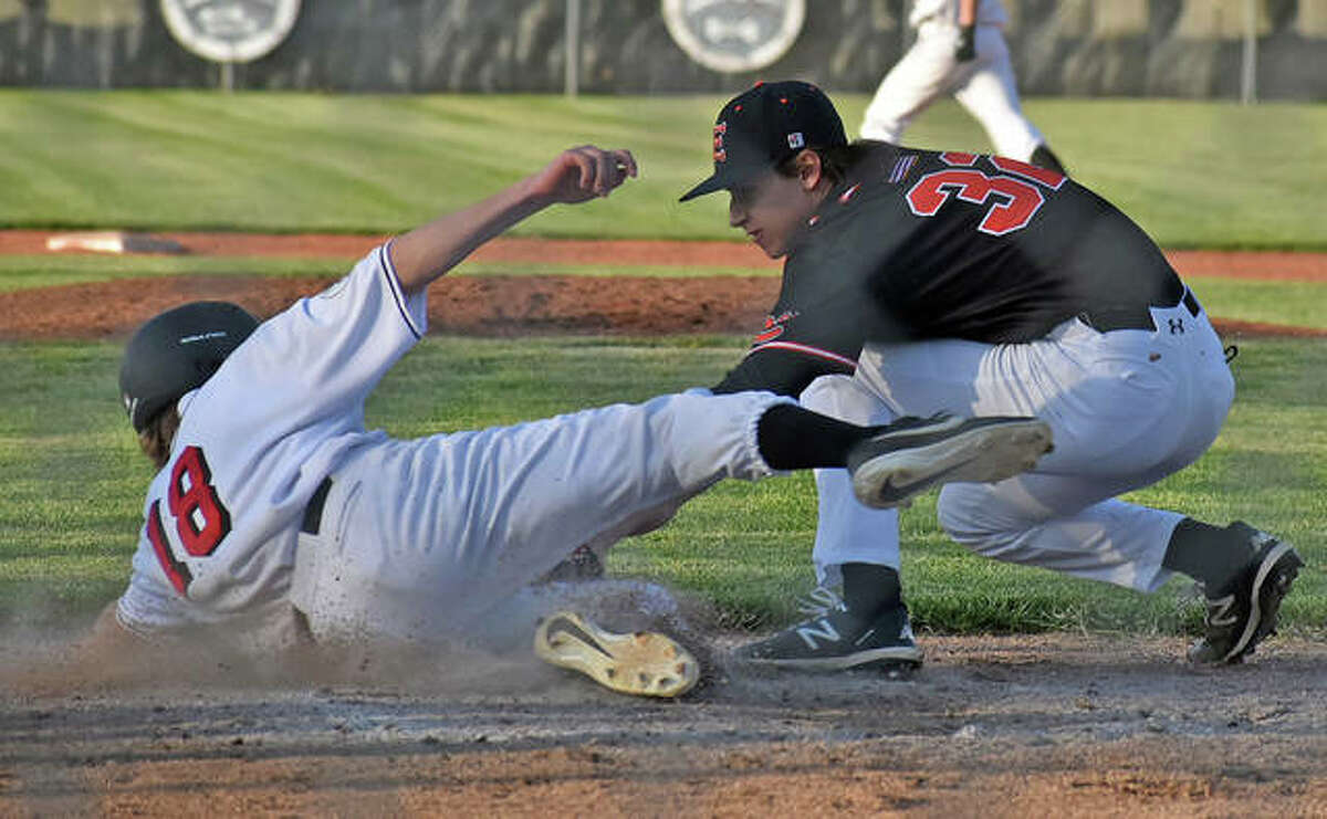 Edwardsville relief pitcher Caden Archer tags out a Highland base runner at home plate attempting to score on a pitch in the dirt.