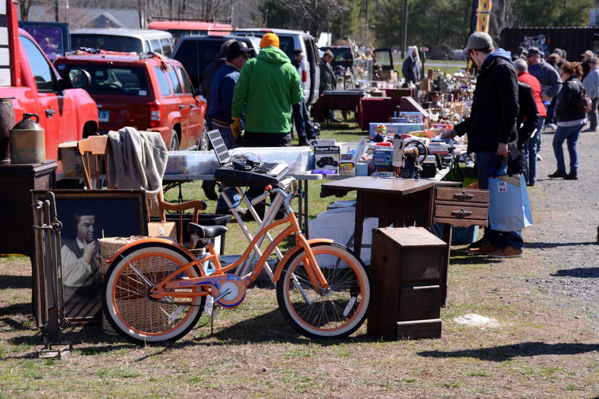  An image of a flea market with people searching through piles of old junk and hidden treasures.