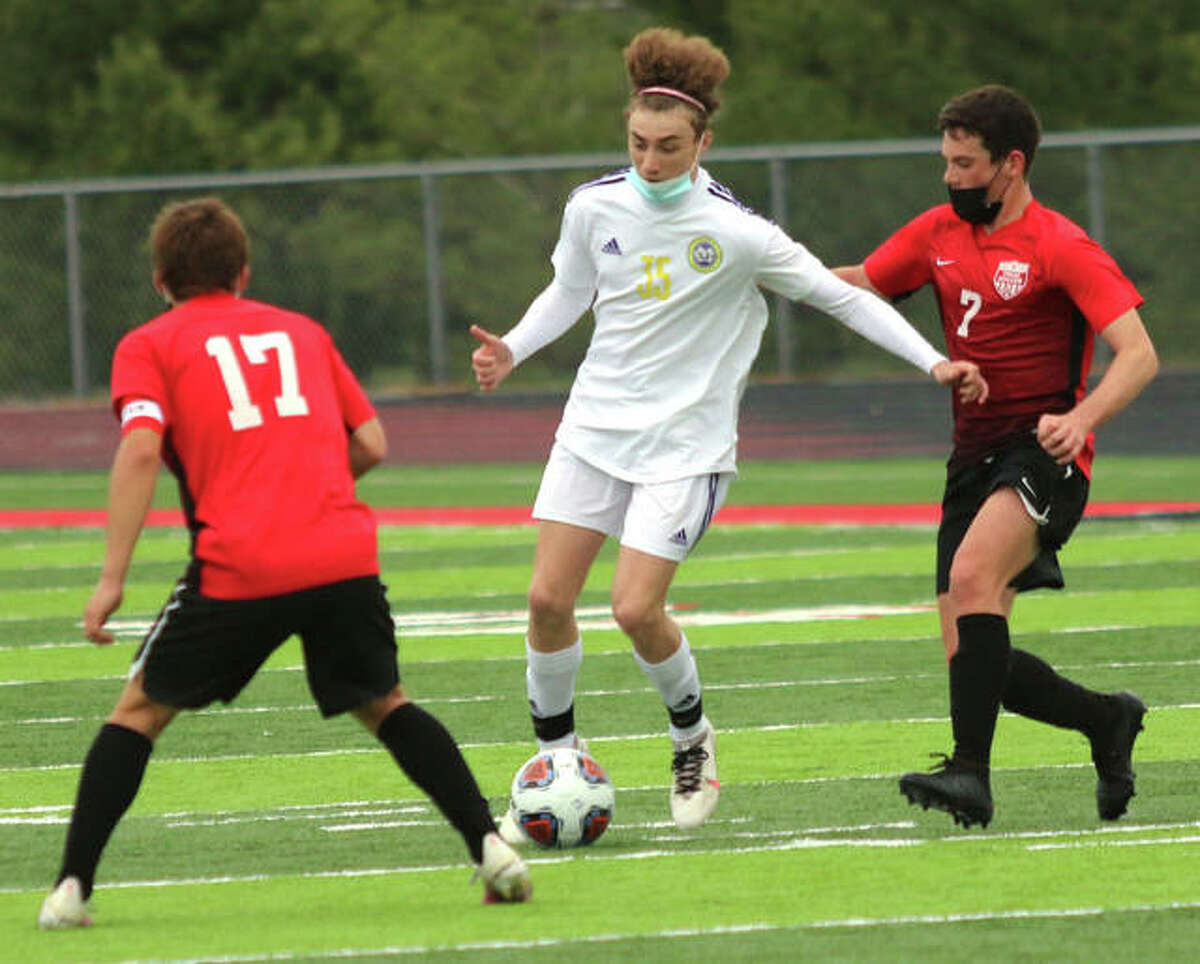 CM’s Bryce Davis, center, scored a pair of goal Tuesday in his team’s 4-2 loss to Triad. He is pictured earlier in the season against Triad in Troy, handling the ball between Triad’s Eli Kraabel (17) and Cameron Ramirez.