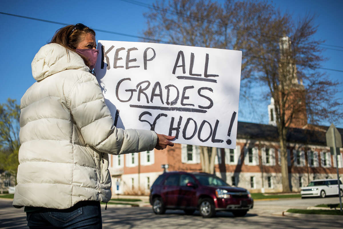 Annmarie Erickson stands among about 50 concerned individuals - most of them parents - while they gather along Rodd Street in front of Central Park Elementary Wednesday, April 14, 2021 to protest Midland Public Schools' decision to suspend in-person classes and school sports in grades 6-12 from April 13-23. (Katy Kildee/kkildee@mdn.net)