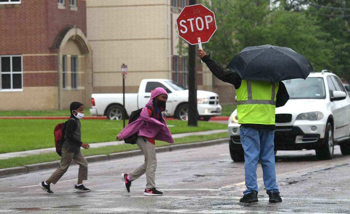 A crossing guard assists Pietzch-MacArthur students as they cross Highland Avenue in a late afternoon rainfall Wednesday. Photo made Wednesday, April 14, 2021 Kim Brent/The Enterprise