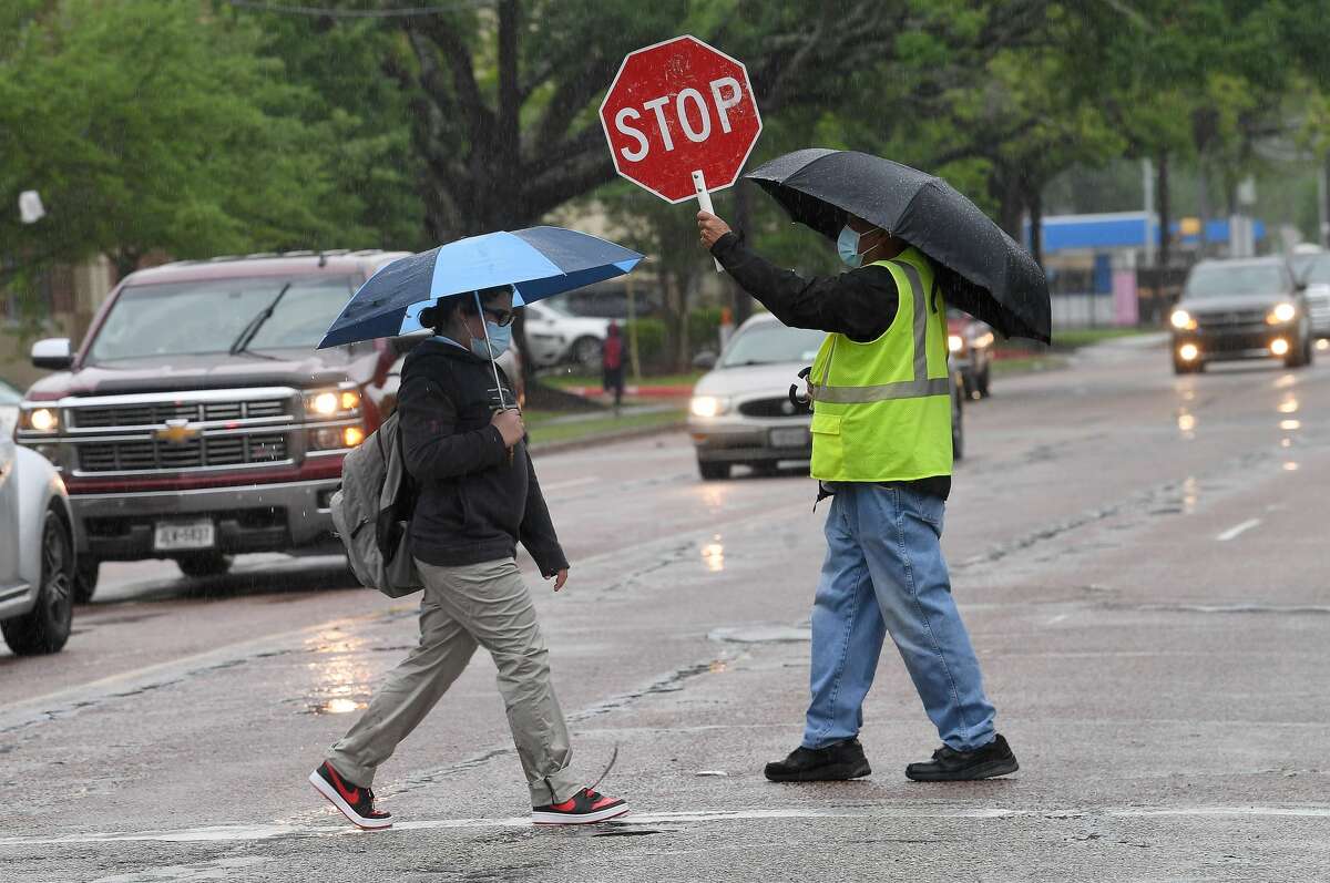 A crossing guard assists Pietzch-MacArthur students as they cross Highland Avenue in a late afternoon rainfall Wednesday. Photo made Wednesday, April 14, 2021 Kim Brent/The Enterprise