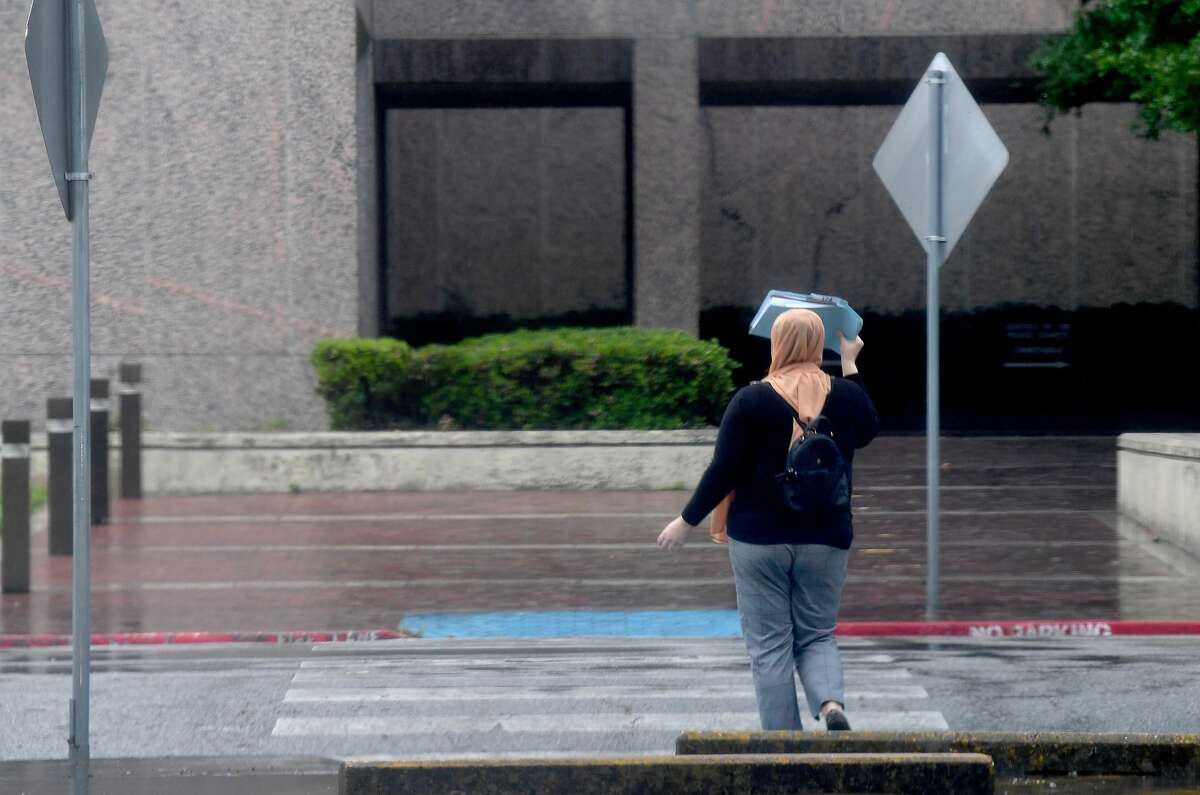A woman covers her head from the rain while walking to the Jefferson County Courthouse as rain and storms make their way through the area Wednesday morning. The weather system will remain in the area the remainder of the week. Photo made Wednesday, April 14, 2021 Kim Brent/The Enterprise