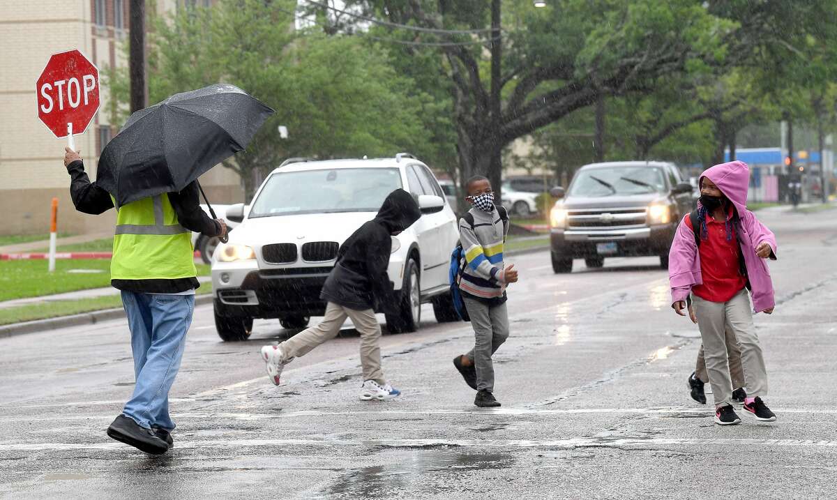A crossing guard assists Pietzch-MacArthur students as they cross Highland Avenue in a late afternoon rainfall Wednesday. Photo made Wednesday, April 14, 2021 Kim Brent/The Enterprise