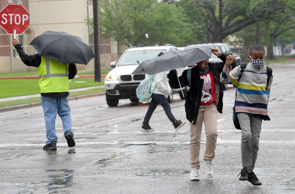 A crossing guard assists Pietzch-MacArthur students as they cross Highland Avenue in a late afternoon rainfall Wednesday. Photo made Wednesday, April 14, 2021 Kim Brent/The Enterprise