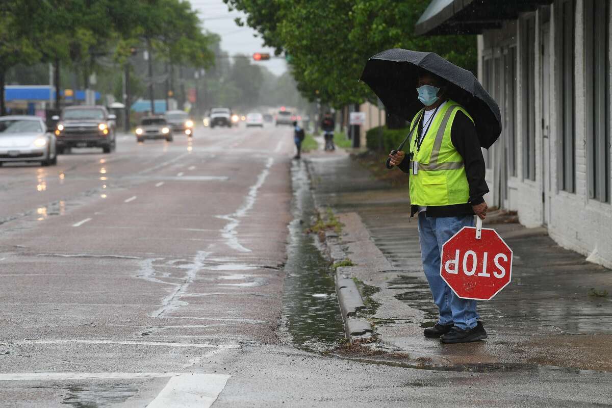 A crossing guard waits to assist Pietzch-MacArthur students across Highland Avenue in a late afternoon rainfall Wednesday. Photo made Wednesday, April 14, 2021 Kim Brent/The Enterprise