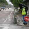 A crossing guard waits to assist Pietzch-MacArthur students across Highland Avenue in a late afternoon rainfall Wednesday. Photo made Wednesday, April 14, 2021 Kim Brent/The Enterprise