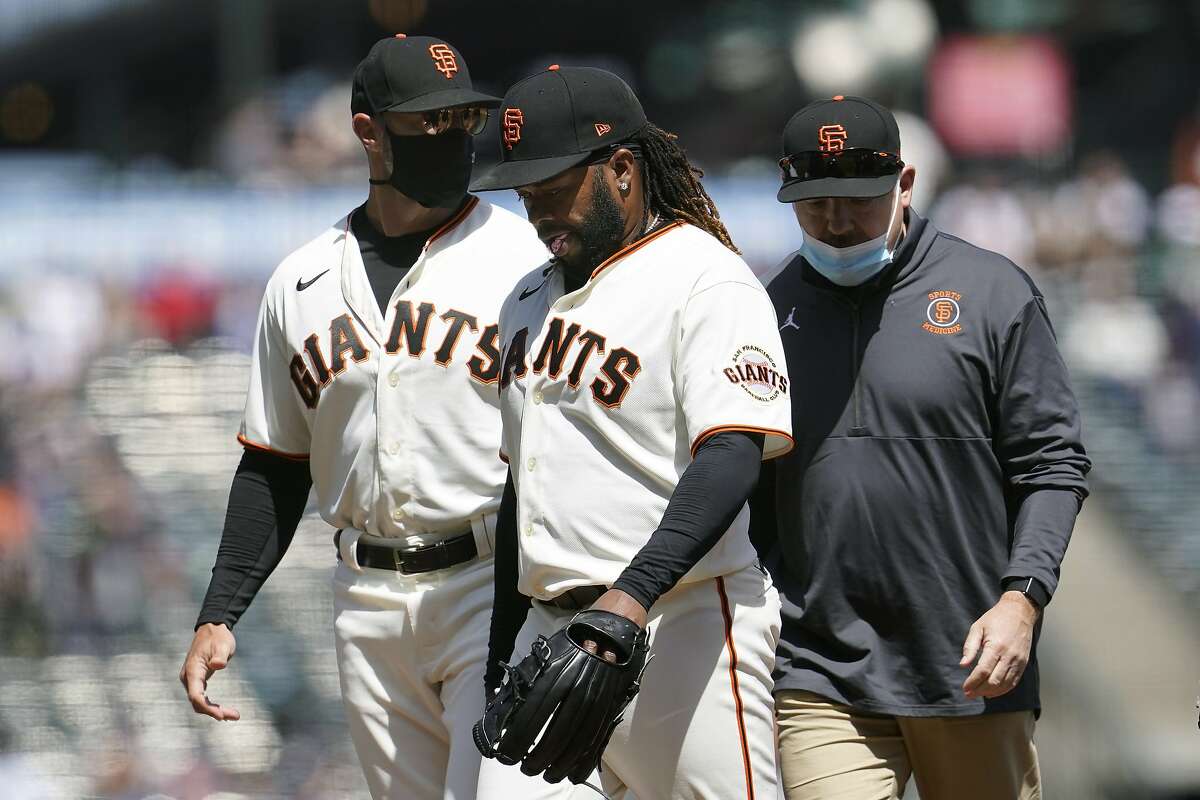 San Francisco Giants starting pitcher Johnny Cueto, middle, walks toward the dugout next to manager Gabe Kapler, left, as he leaves the game during the sixth inning of a baseball game against the Cincinnati Reds in San Francisco, Wednesday, April 14, 2021. (AP Photo/Jeff Chiu)