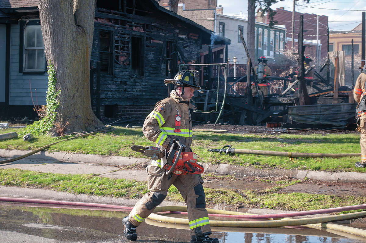 Firefighters battle a blaze Wednesday at an East College Avenue house that destroyed one structure and spread to one of the walls of a nearby restaurant.