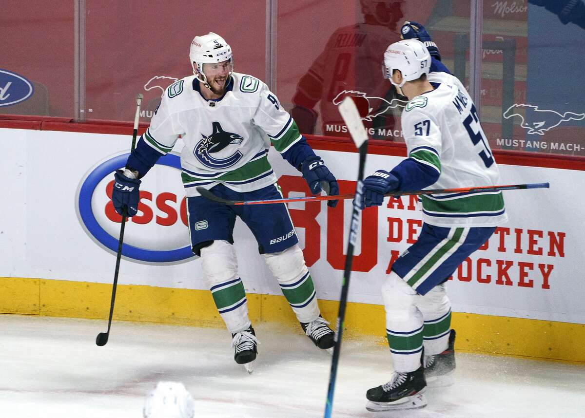 Vancouver Canucks' J.T. Miller, left, celebrates his overtime goal against the Montreal Canadiens with Tyler Myers in an NHL hockey game Friday, March 19, 2021, in Montreal. (Paul Chiasson/The Canadian Press via AP)