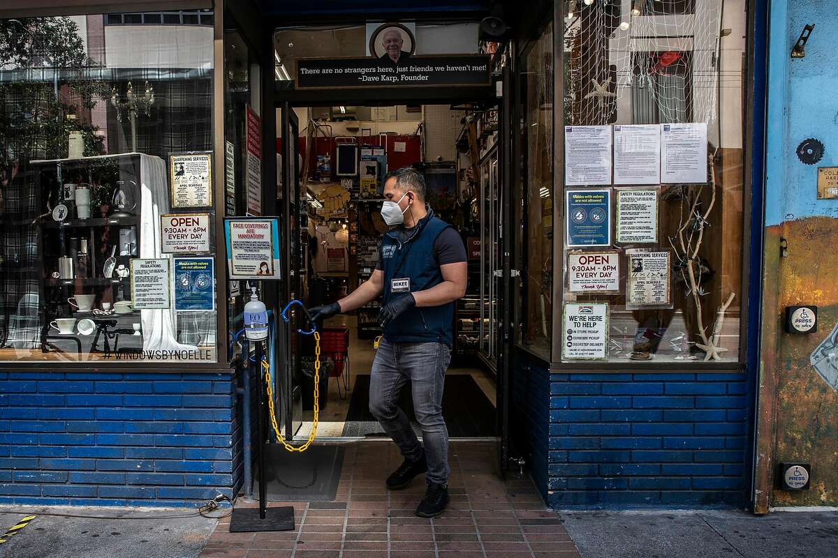 Michael Garde moves a chain at the entrance to limit the number of customers amid the ongoing COVID-19 pandemic at Cole Hardware in Downtown San Francisco, California Wednesday, April 14, 2021.
