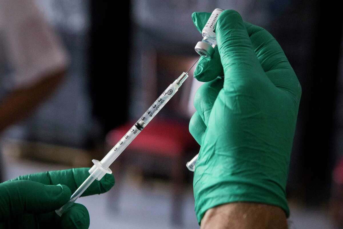Pablo De Angulo, M.D., of Texas Vaccine Institute, fills a syringe with Pfizer BioNTech COVID-19 vaccine during a clinic for Legacy Restaurants group employees in April in Houston. As active COVID-19 cases continue to drop in the region, the number of deaths related to the virus continue to climb in Montgomery County.