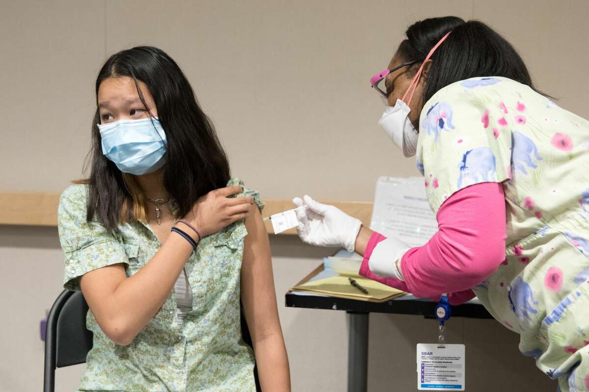 Emma Yin, 16, receives a COVID-19 vaccine at UCSF Benioff Children Hospital from nurse Melani Wells in Oakland, Calif. on April 15, 2021. It was the first day that anyone over 16 years old in California could receive the COVID-19 vaccine.