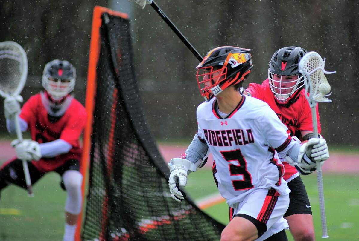 Ridgefield’s Ryan Colsey (3) comes from behind the goal with the ball as New Canaan’s Braden Sweeney (91) defends on Thursday.