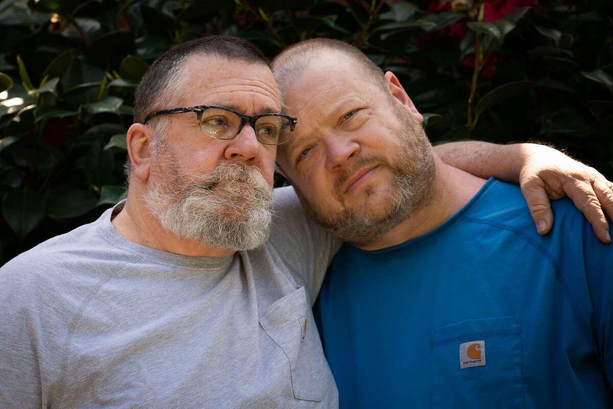 Tom Baker (left) and husband Chad Baker, an emergency room nurse at Kaiser, stand outside their home in San Leandro on Monday. “He was there on the front lines,” Tom said about his husband Chad. “He is a real hero.”