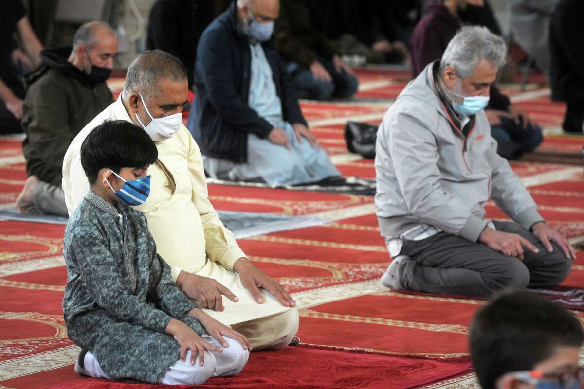 Khadim Khan and his son Mihad join other worshipers as they gather to pray on the first Friday of the Islamic holy month of Ramadan, at the Bridgeport Islamic Community Center, in Bridgeport, Conn. April 16, 2021. The global COVID-19 health crisis struck Connecticut in March 2020, shuttering businesses, canceling events and forcing the public to stay home as much as possible to stop the illness’s spread. Faith organizations in general were forced to adapt and offer on-line services to members. And the sudden sense of isolation at the time was particularly acute for major faiths — Muslims, Jews and Christians — that, respectively, celebrate Ramadan, Passover and Easter in the spring.