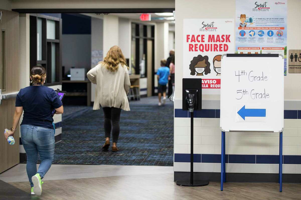 McElwain Elementary School staff members, pictured in September 2020, walk past signs reminding people of the requirement to wear a mask at the Katy ISD campus. Katy Superintendent Ken Gregorski said Friday that the district does not plan to require masks at campuses starting June 1.