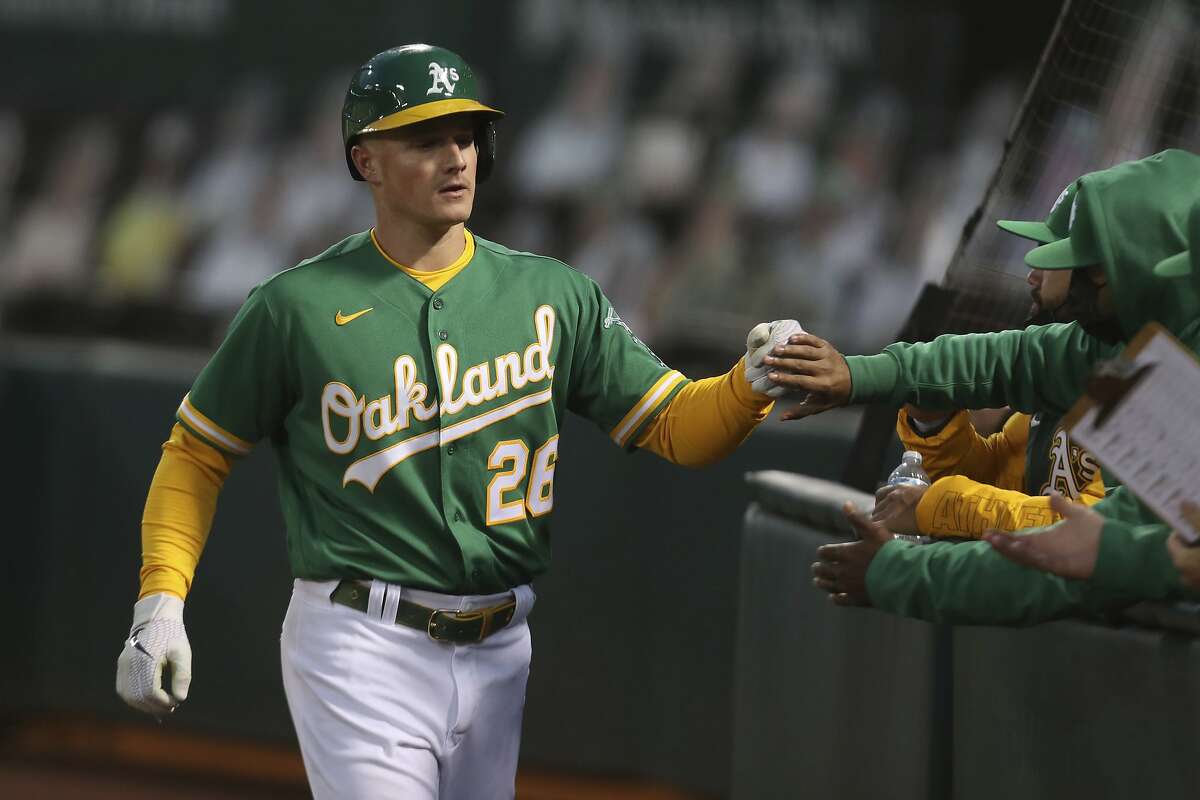 Oakland Athletics' Matt Chapman is congratulated by teammates after scoring on a single by Sean Murphy against the Detroit Tigers during the fourth inning of a baseball game in Oakland, Calif., Friday, April 16, 2021. (AP Photo/Jed Jacobsohn)