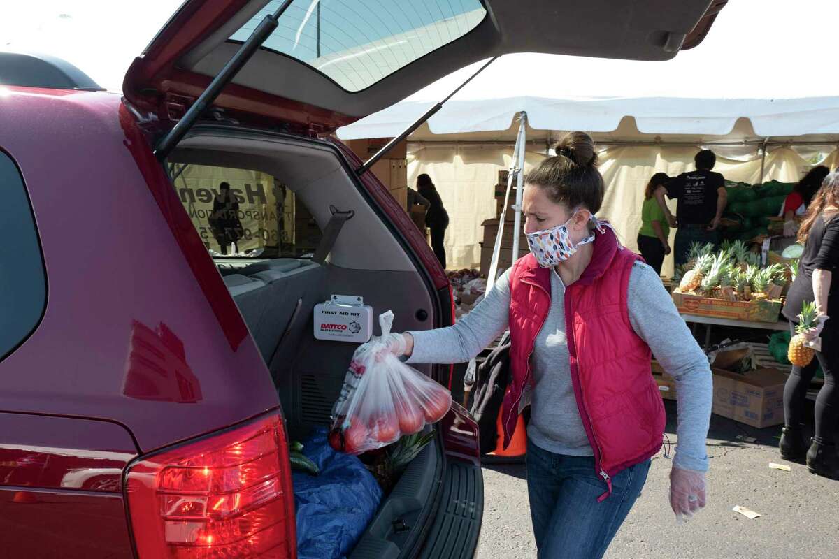 A volunteer places a bag of tomatoes into a slowly moving vehicle at a Foodshare distribution center at Rentschler Field in East Hartford, Connecticut, May 7, 2020, during the coronavirus pandemic.