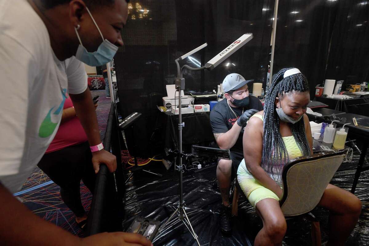 Diontae Thompson jokes with his mother Agnes Charles as she gets her very first tattoo from San Antonio artist Jacob Ramos on the opening day of this weekend's Ink Masters Tattoo Show at the MCM Elegante in Beaumont. Renowned tattoo artists from the region will be scheduling appointments and doing walk-up tattoos, and other vendors are on-site, as well. The event continues Saturday 11 a.m. - 11 p.m., and Sunday 11 a.m. - 9 p.m. Photo made Friday, April 16, 2021 Kim Brent/The Enterprise