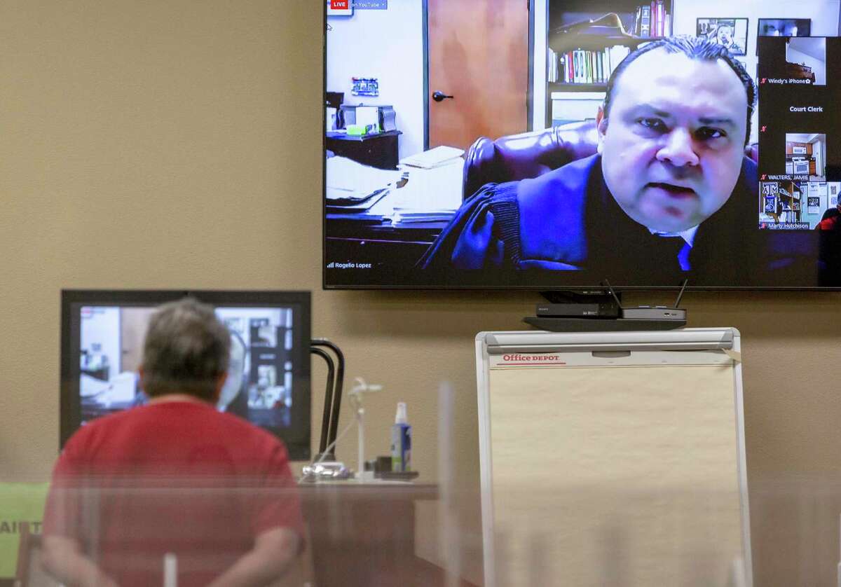 Justice of the Peace Precinct 4 Judge Rogelio Lopez appears on screen while a landlord listens Wednesdayduring a hybrid online/in-person eviction hearing.