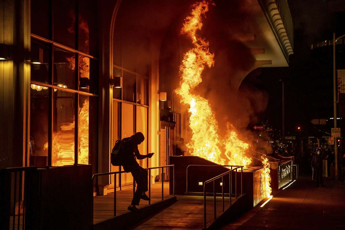Demonstrators set fire to the front of the California Bank and Trust building during a protest against police brutality in Oakland, Calif., on Friday, April 16, 2021.