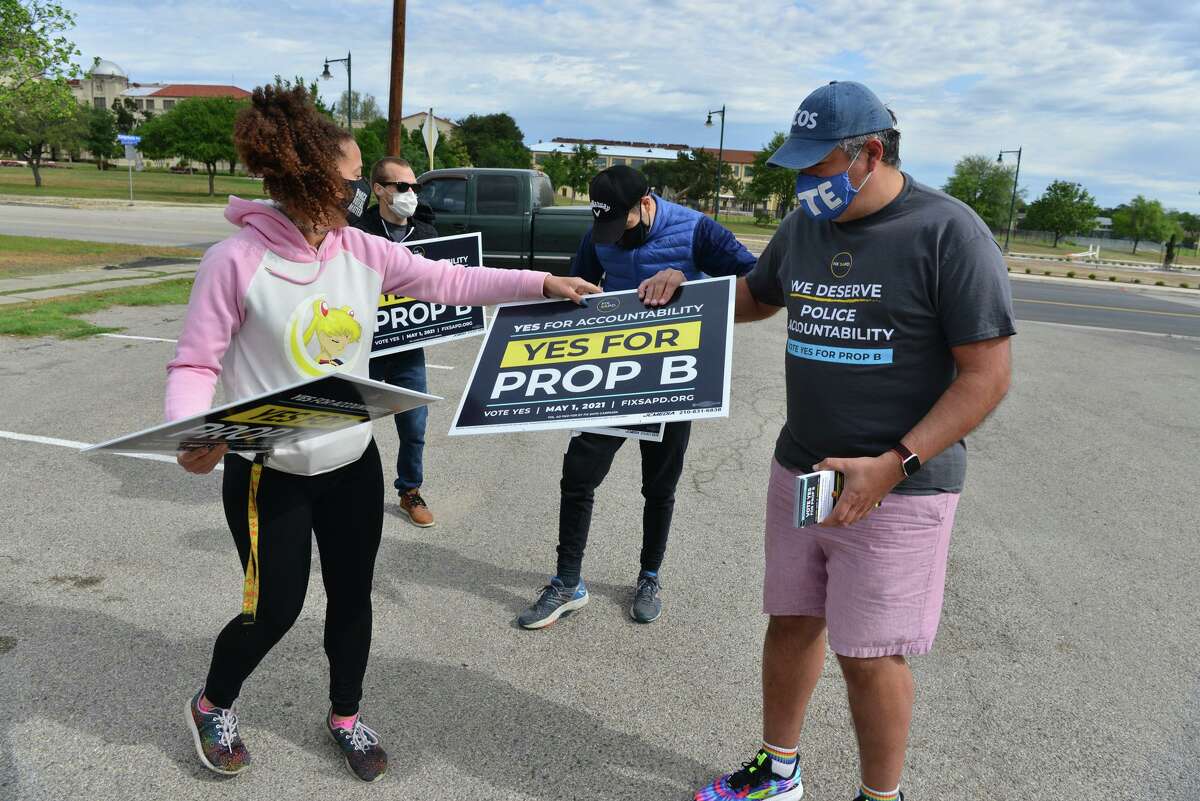 Ananda Tomas, deputy director of Fix SAPD, hands out yard signs to volunteer Arturo Ordoqui. Fix SAPD is a leader in efforts to pass Proposition B.