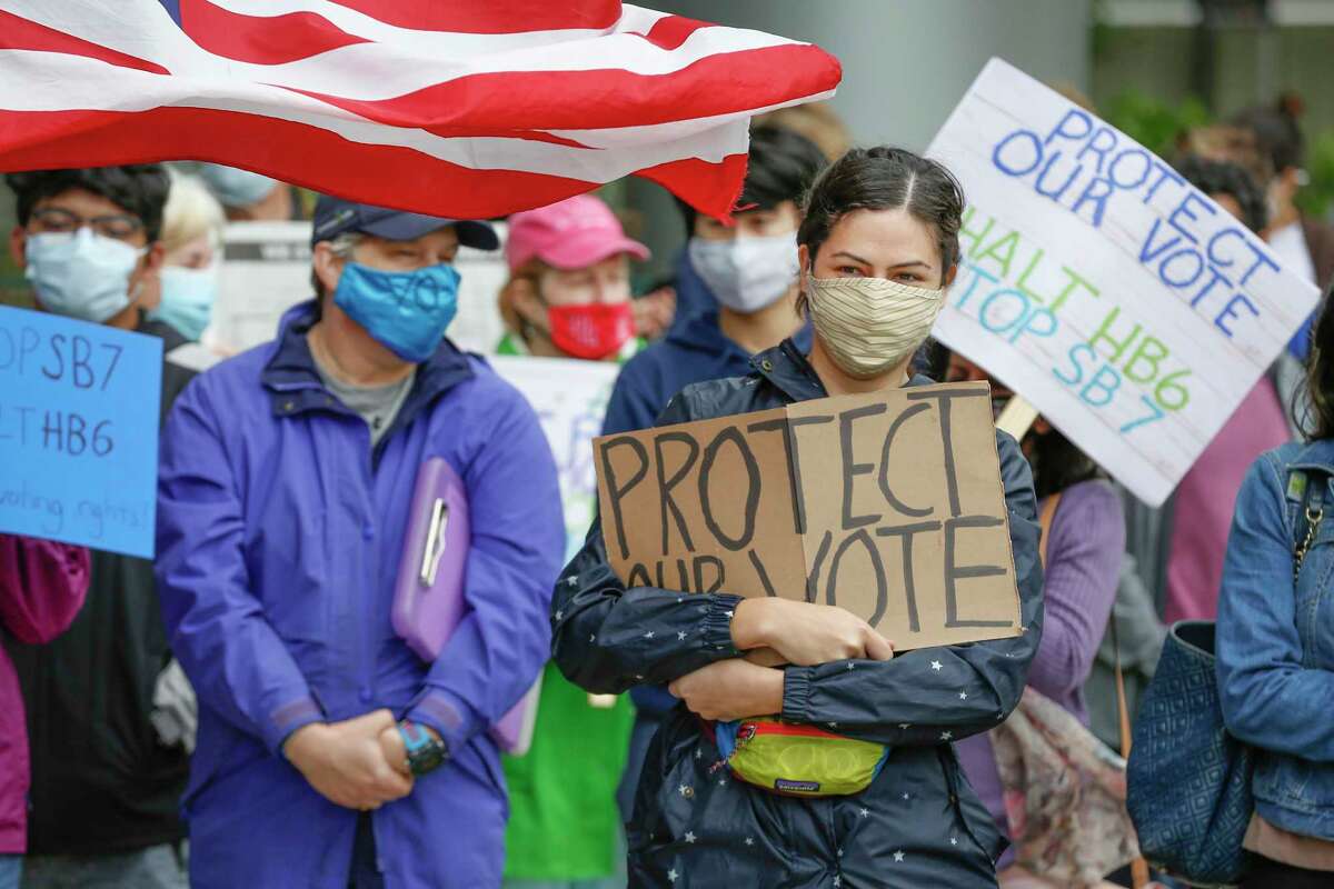 Sarah Bronson holds a sign and attempts to stay warm with voters and activist organizations as they gathered at the Greater Houston Partnership building to demand the business group oppose the voter bills being considered by the Texas legislature Saturday, April 17, 2021, in Houston.