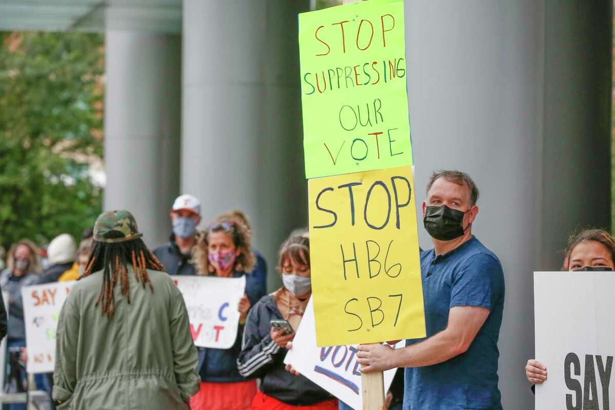 Cody Pogue (second from right) holds a sign with other voters and activist organizations as they gathered at the Greater Houston Partnership building to demand the business group oppose the voter bills being considered by the Texas legislature Saturday, April 17, 2021, in Houston.