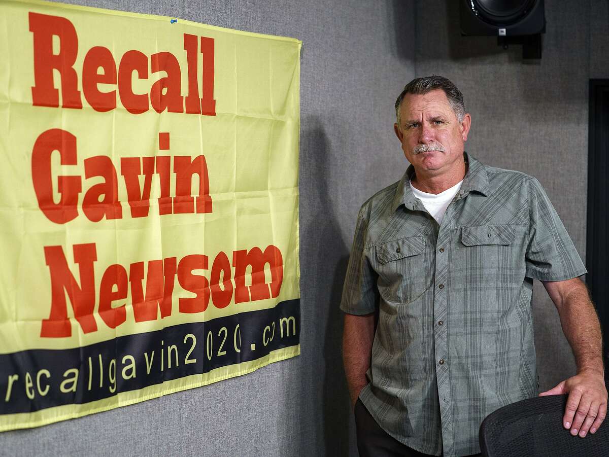 Orrin Heatlie, the main organizer for the Recall of California Gov. Newsom campaign, poses with a banner before recording a radio program at the KABC radio station studio in Culver City (Los Angeles County) on March 27, 2021.