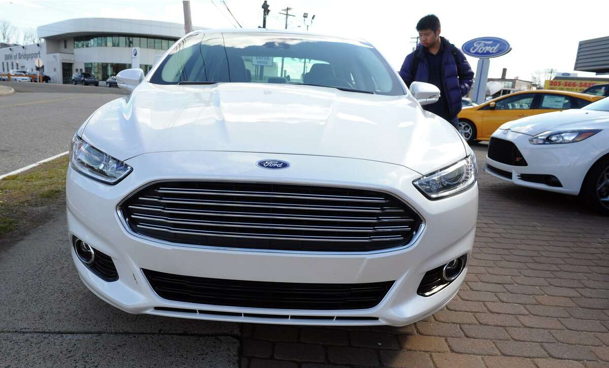 A young man takes a look at the newest Ford Fusion electric hybrid on display outside Park City Ford in Bridgeport, Conn. on Tuesday April 2, 2013. New car sales have risen to a six-year high last month and dealership President David Flint says sales from his lot has gone up 22 percent from a year ago.