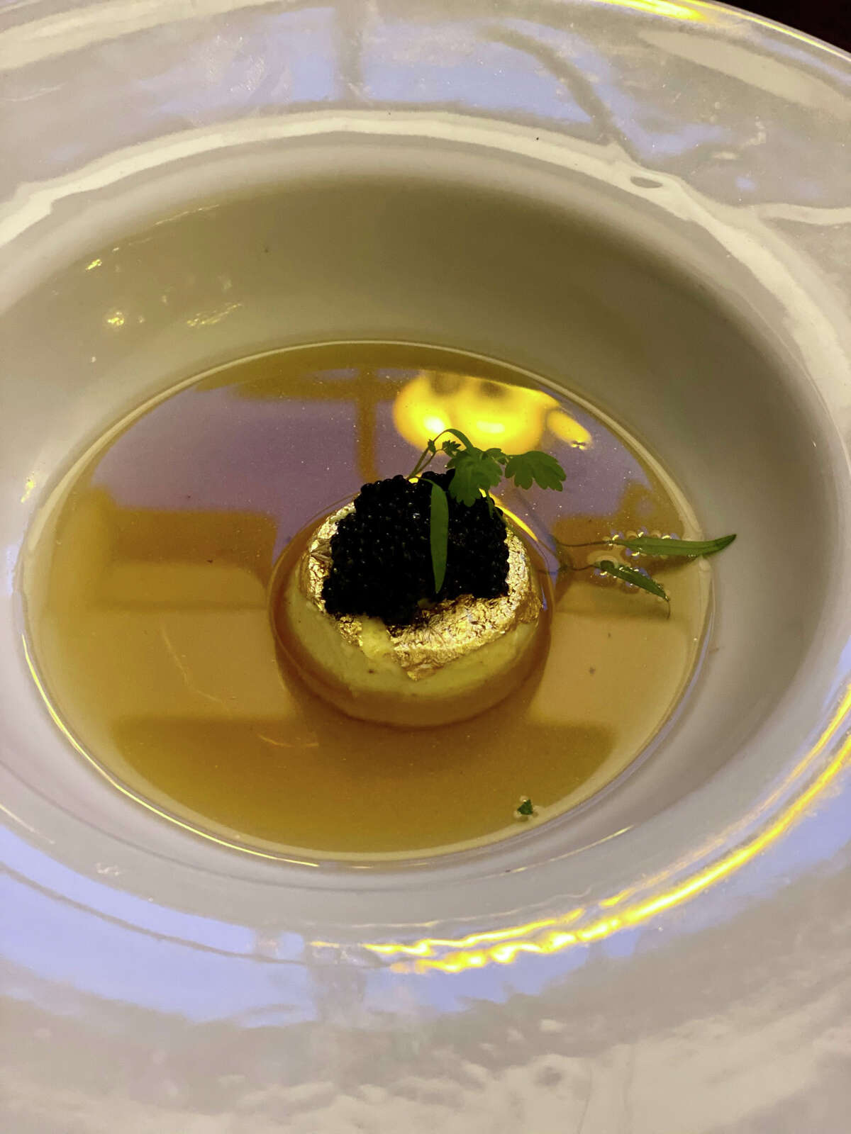 Edible gold foil wraps a savory custard that is topped with caviar and bathed in crystal-clear bison consommé at Jack's Oyster House in Albany.