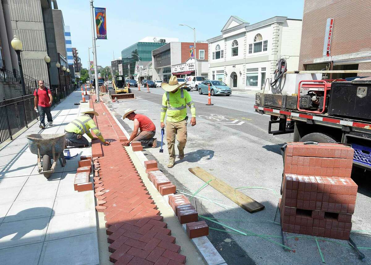 A crew from Colonna Concrete and Asphalt Paving out of West Haven lay out a decorative edging to a new sidewalk along Summer Street in Stamford, Conn. on July 16, 2019. The crew of four each were wearing large straw caps to help shade themselves from the heat of the sun. Temperatures in the region reach into the 90's with no expected relief in the coming days.