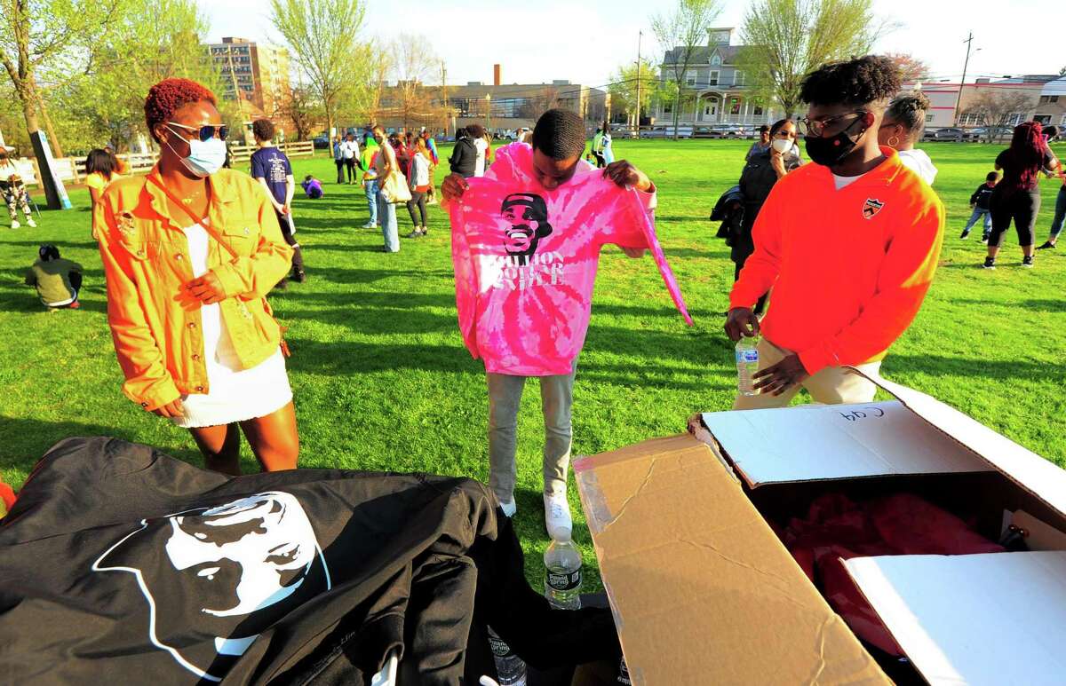 Nasair Dublin, center, checks out a pink hoodie to buy during Max Antoine Day, a memorial and anti-gun rally for the late Stamford resident killed in 2017, at Jackie Robinson Park in Stamford, Conn., on Tuesday April 20, 2021. At left is Max's daughter Cheyenne Antoine. After issuing a proclamation to the event, Mayor David Martin addressed Stamford's most recent bout of gun violence.