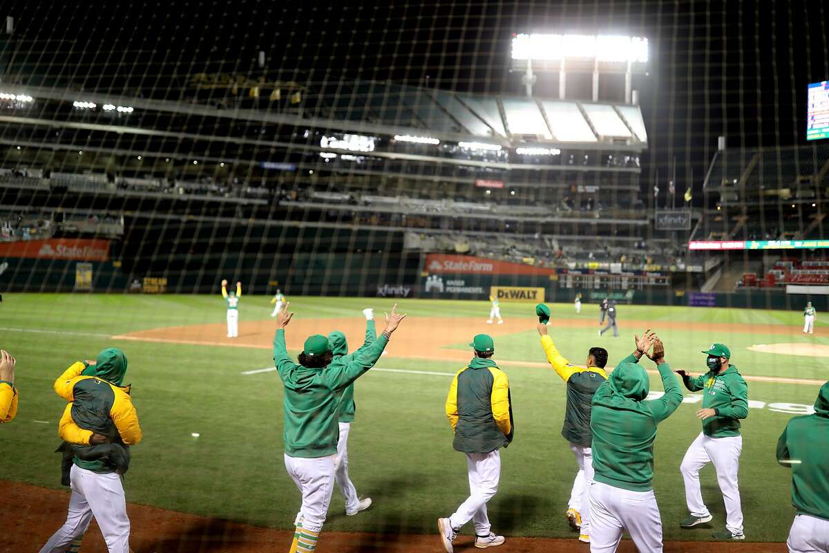 The dugout runs out after Oakland Athletics left fielder Mark Canha (20) makes the final out for the win against the Minnesota Twins in the second game of an MLB doubleheader at RingCentral Coliseum on Tuesday, April 20, 2021, in Oakland, Calif. The A’s won 1-0.