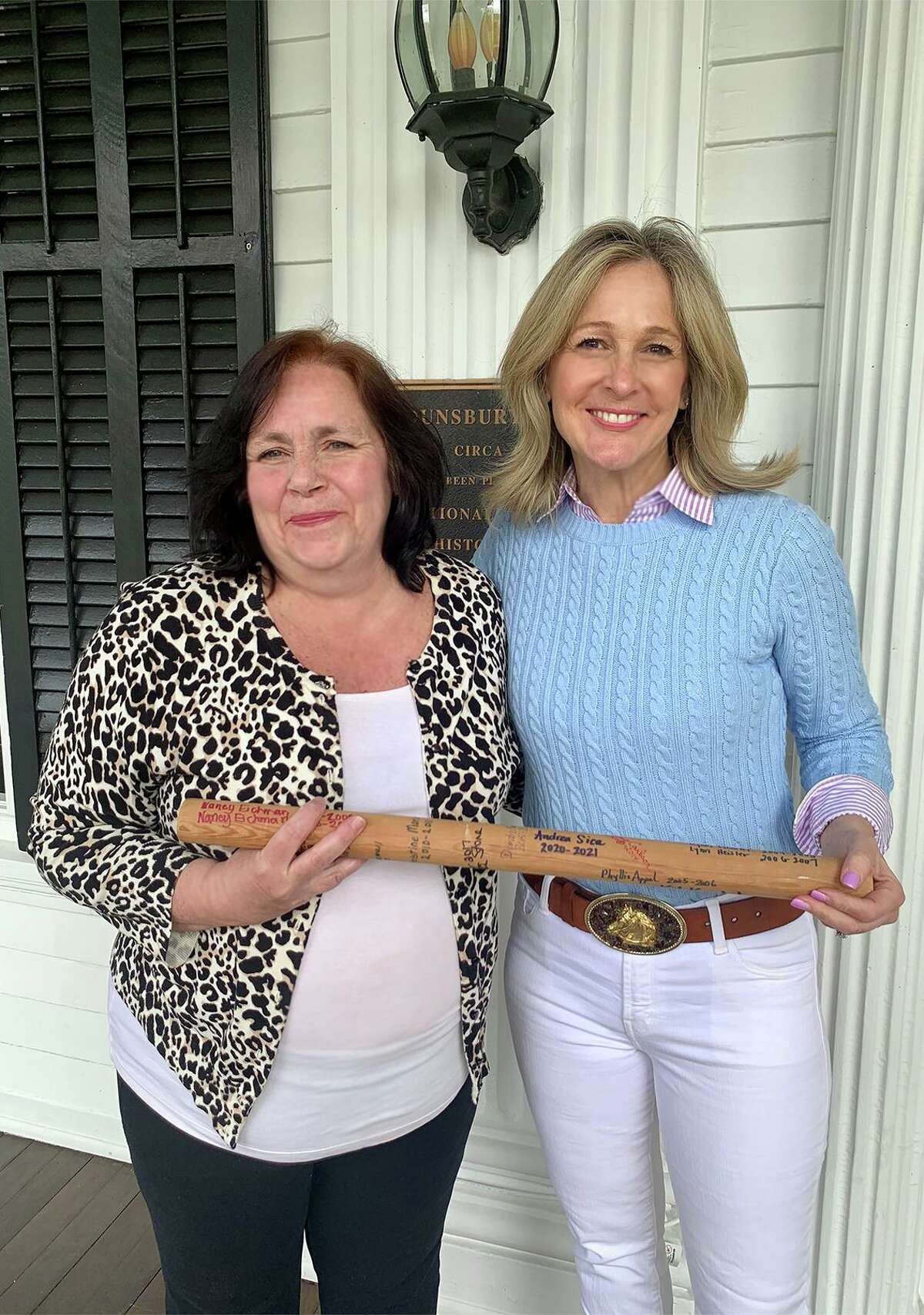LouAnne Cazalet, left, and Andrea Sica hold a baton that is passed from president to president of the National Charity League’s Nutmeg Chapter, which is celebrating its 20th anniversary this year.