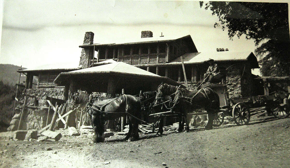 A historic photo shows a wagon stopped in front of a nearly completed Wolf House. 