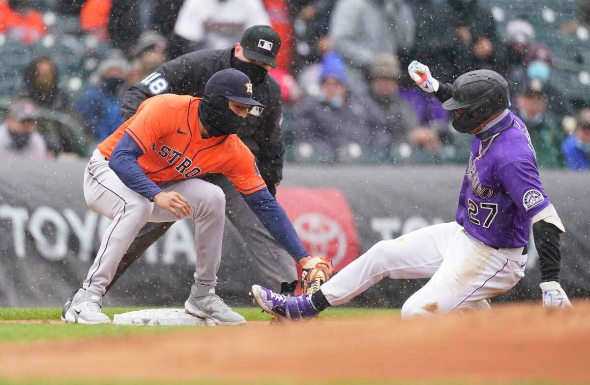 Houston Astros shortstop Carlos Correa, left, tags out Colorado Rockies' Trevor Story at third base as he tries to stretch a double into a triple in the first inning of a baseball game Wednesday, April 21, 2021, in Denver. (AP Photo/David Zalubowski)