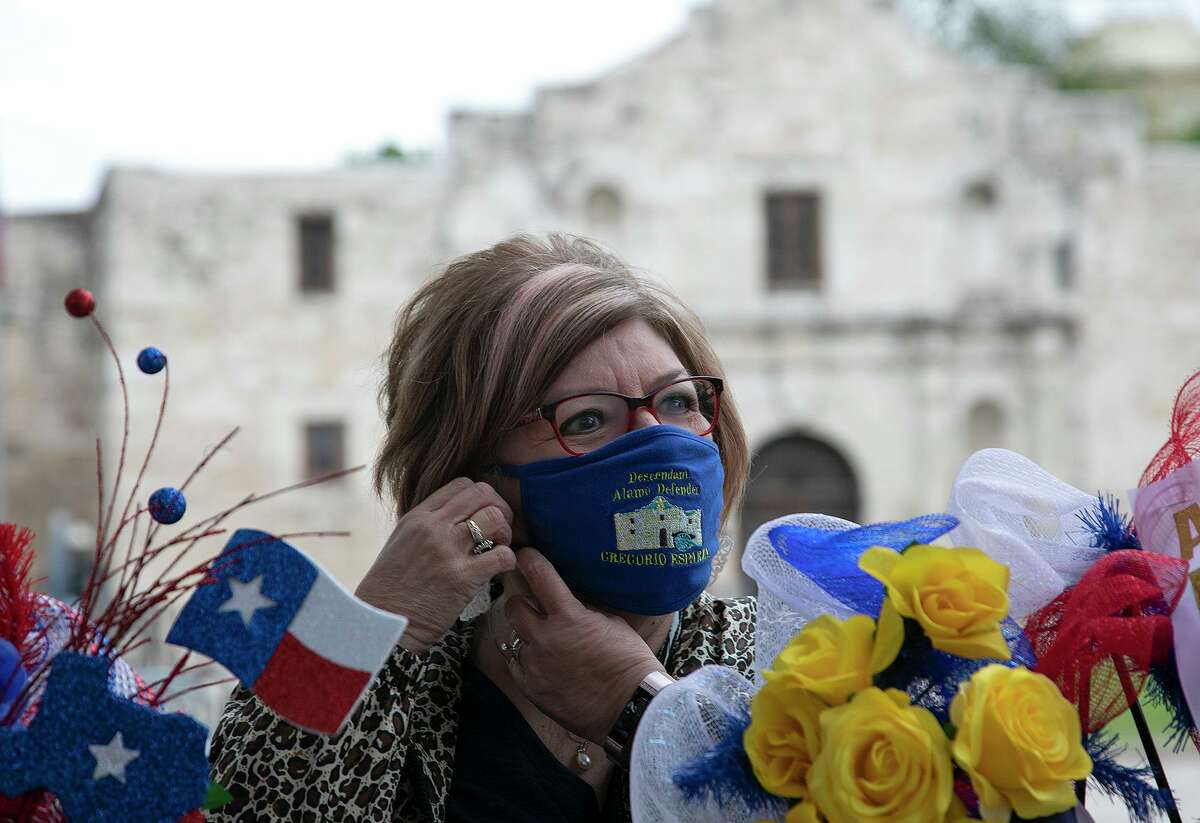 Peggy Huizar Guerrero, a direct descendant of Gregorio Esparza, adjusts her mask bearing his name before placing wreaths in front of the Alamo church in honor of the Battle of San Jacinto and fallen soldiers and volunteers at the Battle of the Alamo on April 21, 2021. The Alamo Couriers chapter and the Alamo Mission chapter of the Daughters of the Republic of Texas gathered to place the wreaths together instead of their annual pilgrimage to the Alamo.