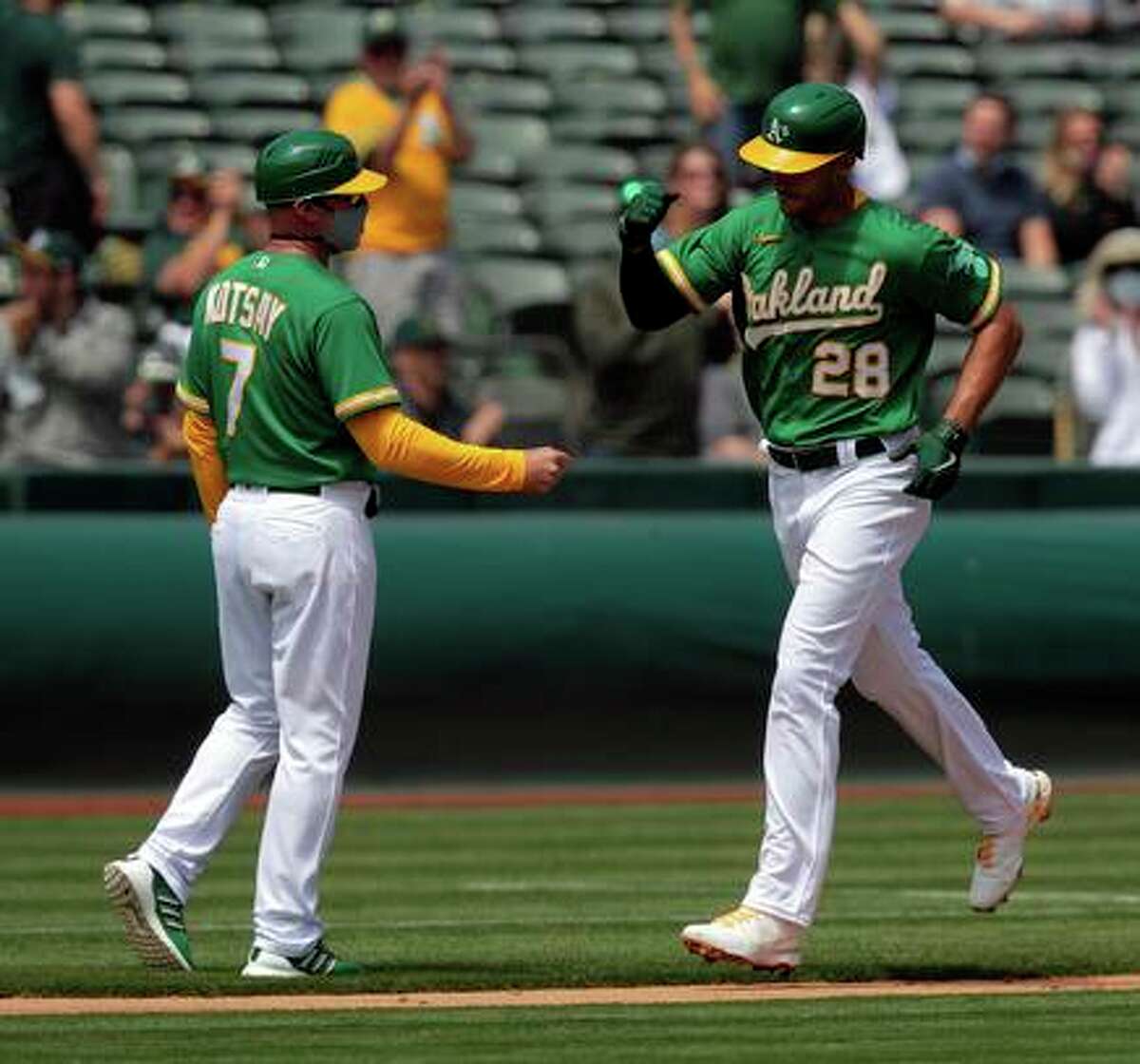 Matt Olson (28) high fives third base coach Mark Kotsay as he rounds the bases on his solo homerun in the second inning as the Oakland Athletics played the Minnesota Twins at the Oakland Coliseum in Oakland, Calif., on Wednesday, April 21, 2021.