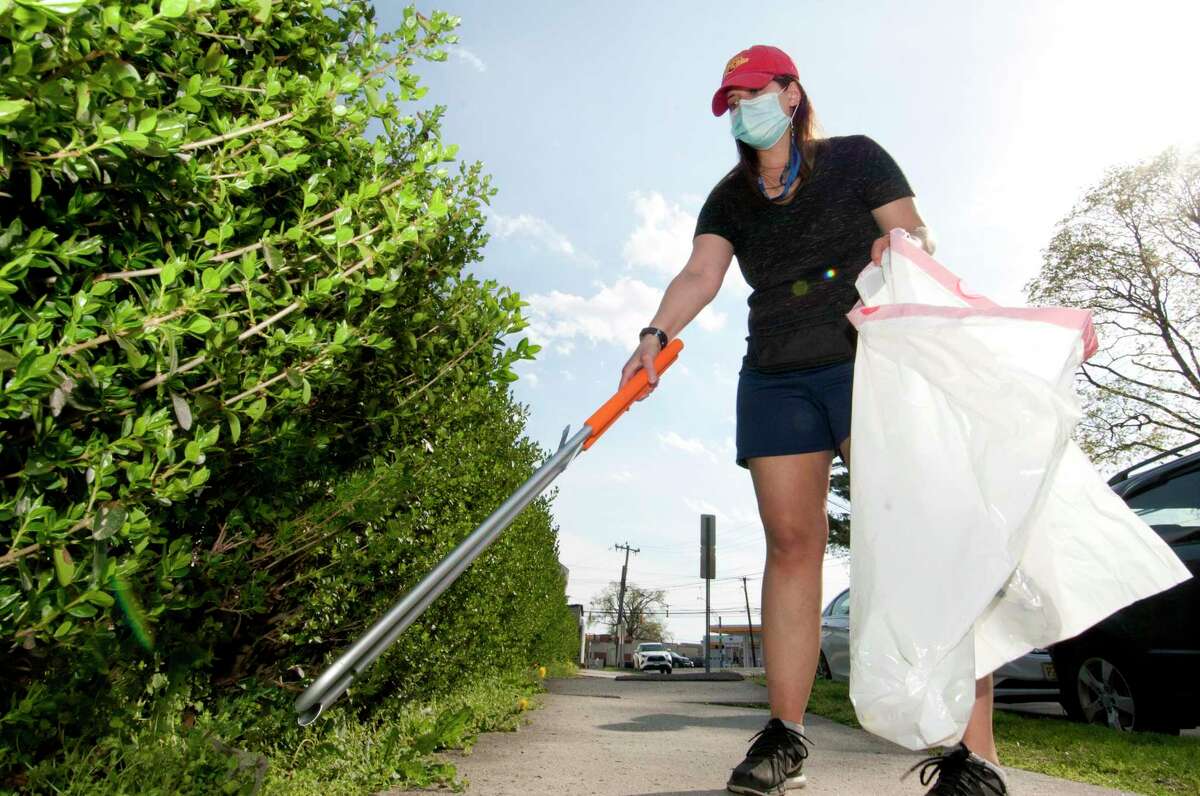 Jessica Hanley picks up trash near her home along Shippan Avenue in Stamford, Conn., on Tuesday April 20, 2021. Hanley, a public school teacher in Greenwich, spends her weekends scavaging the streets for garbage on her Shippan Avenue block and trying to create a greener world, one discarded trash bag at a time.