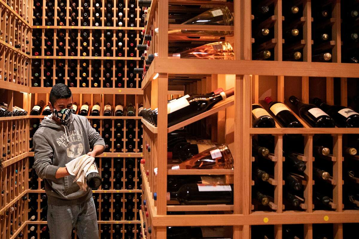 Vidal Mozqueda dusts off bottles of wine that have sat in the cellar untouched since March 2020 as Acquerello in San Francisco prepares for reopening indoor dining next month.